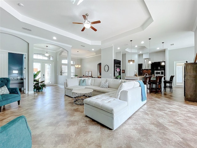 living room with french doors, ceiling fan with notable chandelier, a raised ceiling, and crown molding