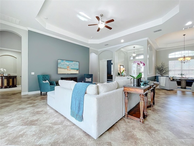 living room featuring ceiling fan with notable chandelier, a tray ceiling, and ornamental molding