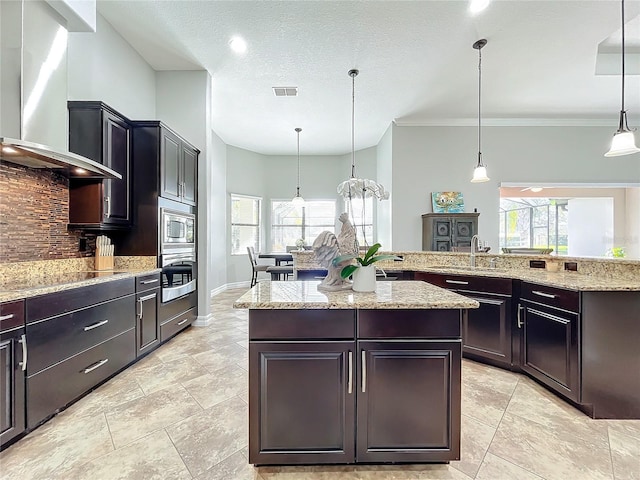 kitchen with backsplash, wall chimney range hood, sink, decorative light fixtures, and stainless steel appliances