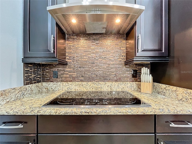 kitchen featuring dark brown cabinets, backsplash, black electric cooktop, and range hood