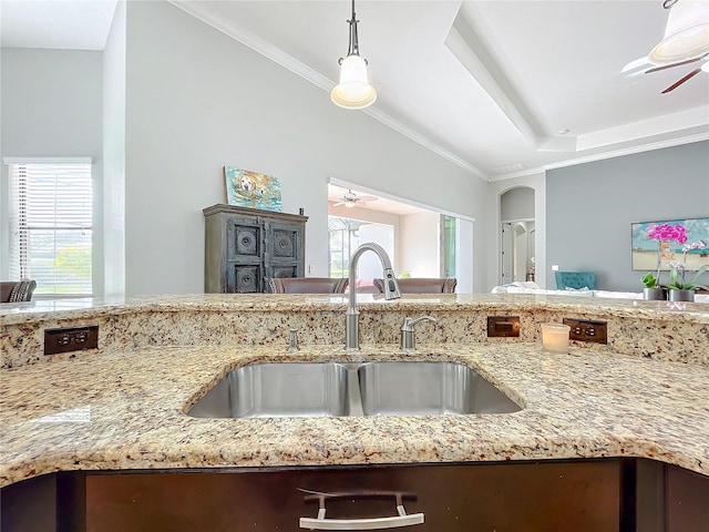 kitchen with crown molding, light stone countertops, sink, and hanging light fixtures