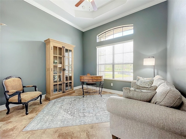 living area featuring a raised ceiling, ceiling fan, and crown molding