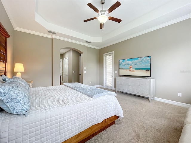 carpeted bedroom featuring a tray ceiling, ceiling fan, and crown molding