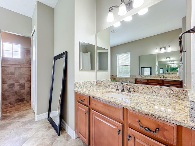 bathroom featuring tiled shower, vanity, and a chandelier