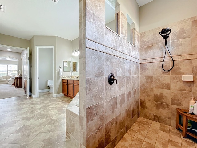 bathroom featuring a tile shower, vanity, and toilet