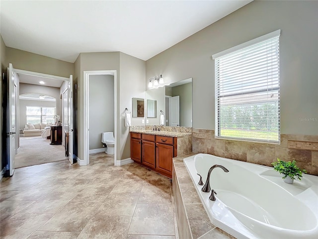 bathroom with vanity, toilet, and tiled tub