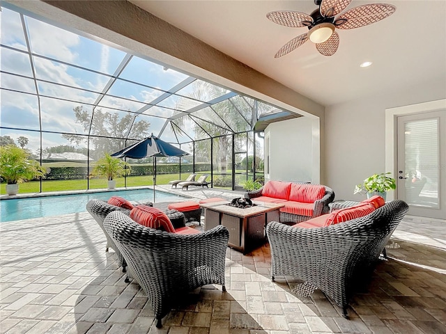 view of patio with a lanai, ceiling fan, and an outdoor living space with a fire pit