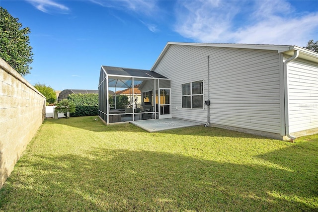 rear view of house featuring a lawn, glass enclosure, and a patio area