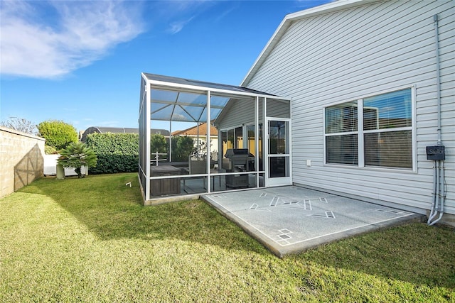 back of house featuring glass enclosure and a yard