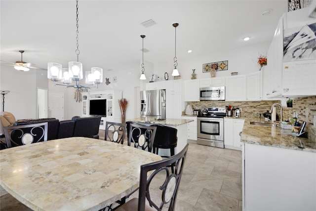 dining room with sink and ceiling fan with notable chandelier