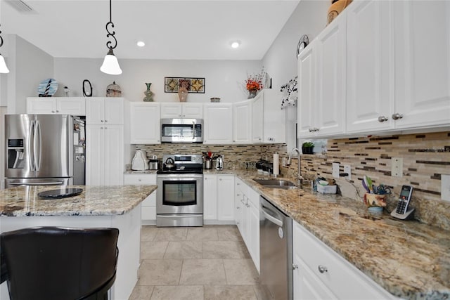 kitchen featuring sink, appliances with stainless steel finishes, decorative light fixtures, light stone counters, and white cabinetry