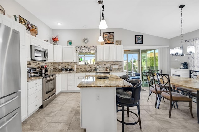 kitchen featuring a center island, stainless steel appliances, vaulted ceiling, and white cabinetry