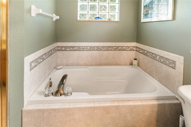 bathroom with toilet and tiled tub