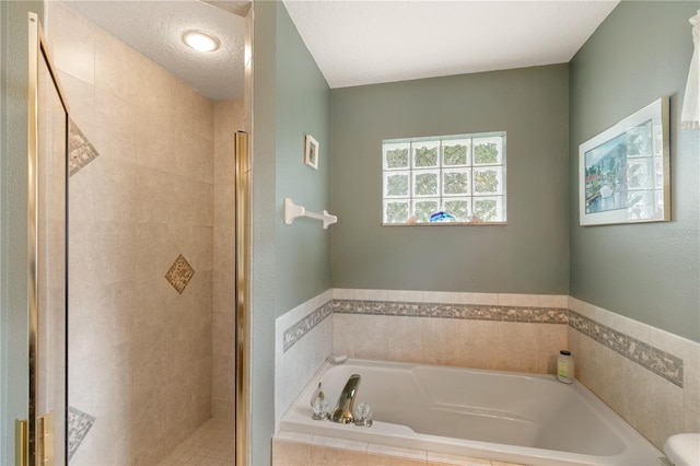 bathroom featuring plus walk in shower and a textured ceiling