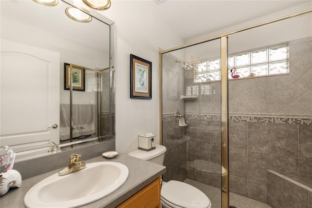 bathroom featuring vanity, toilet, and a shower with shower door