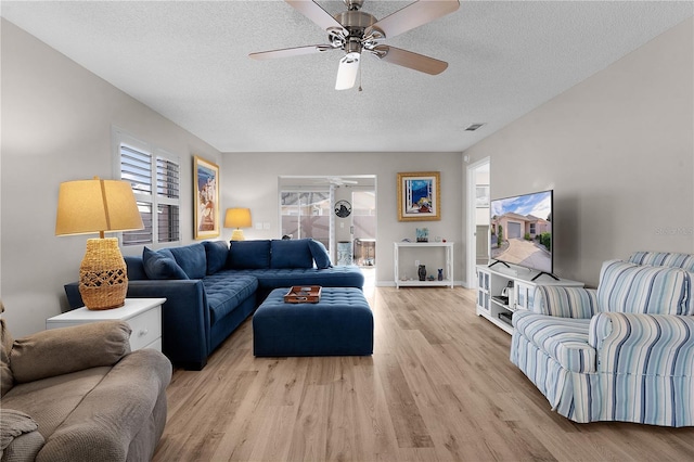 living room with ceiling fan, a healthy amount of sunlight, light hardwood / wood-style floors, and a textured ceiling