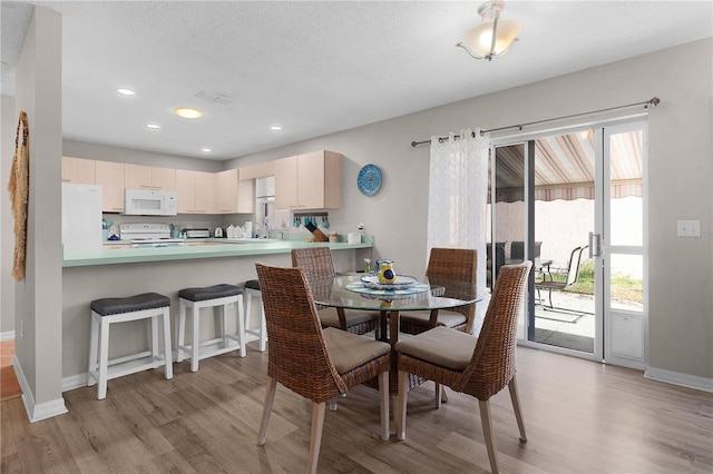 dining area with sink, a textured ceiling, and light wood-type flooring