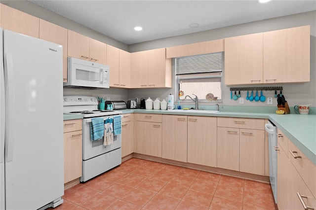 kitchen featuring white appliances, light brown cabinetry, sink, and light tile patterned floors