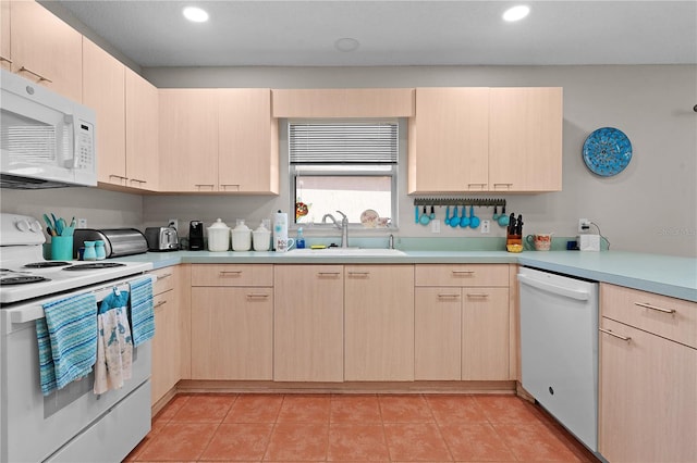 kitchen with sink, white appliances, light tile patterned floors, and light brown cabinets