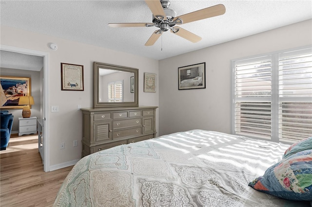 bedroom featuring ceiling fan, light hardwood / wood-style floors, and a textured ceiling