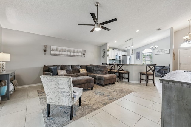 living room with ceiling fan with notable chandelier, a textured ceiling, light tile patterned floors, and lofted ceiling