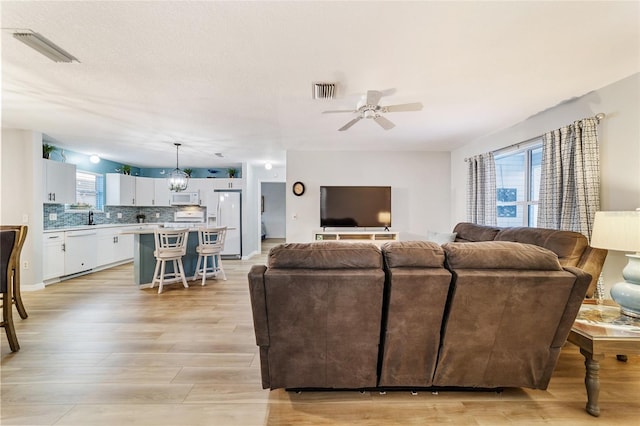 living room with ceiling fan, light wood-type flooring, and sink