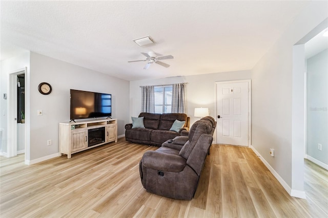 living room with a textured ceiling, light hardwood / wood-style flooring, and ceiling fan