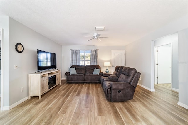 living room with ceiling fan, light hardwood / wood-style flooring, and a textured ceiling