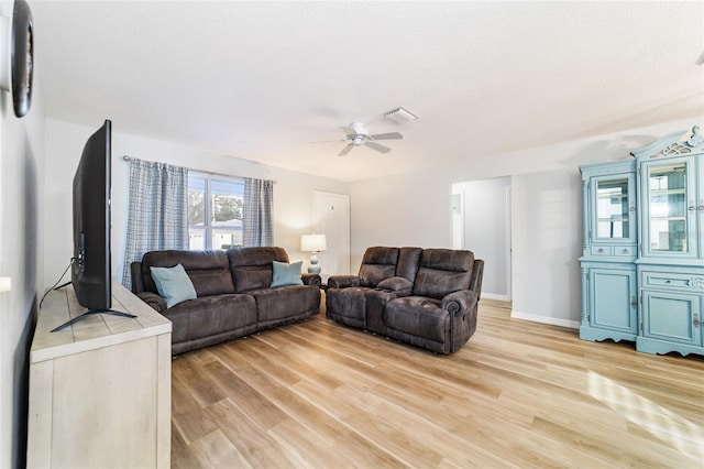 living room featuring ceiling fan, light hardwood / wood-style flooring, and a textured ceiling