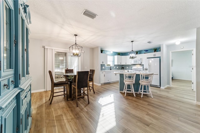 dining room with a chandelier, a textured ceiling, and light hardwood / wood-style flooring