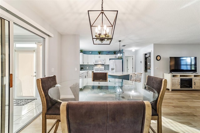 dining space featuring light hardwood / wood-style flooring and a notable chandelier