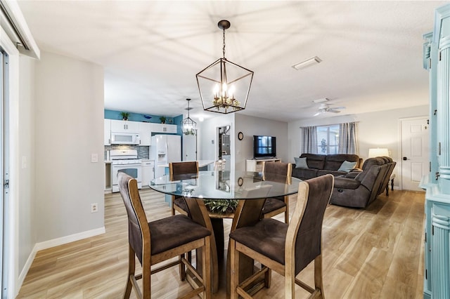 dining area featuring ceiling fan with notable chandelier and light hardwood / wood-style flooring