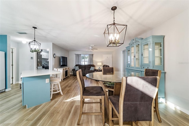 dining room featuring ceiling fan with notable chandelier and light wood-type flooring