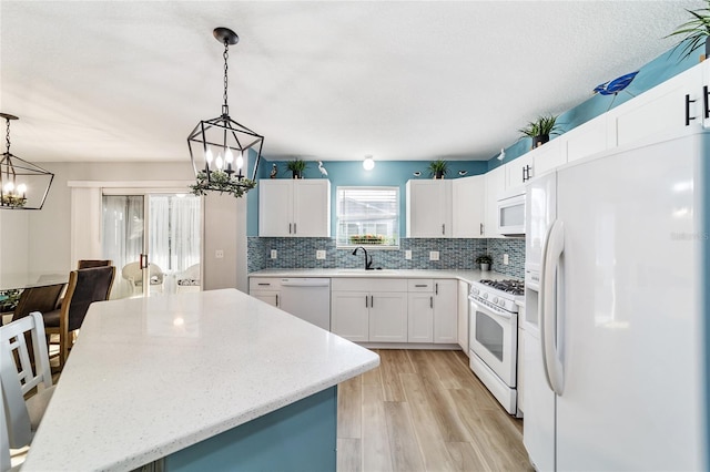 kitchen with white cabinets, white appliances, and decorative light fixtures