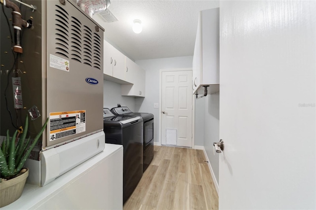 laundry area featuring cabinets, independent washer and dryer, heating unit, and light hardwood / wood-style flooring