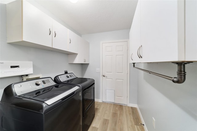 laundry room featuring washer and clothes dryer, cabinets, a textured ceiling, and light hardwood / wood-style flooring