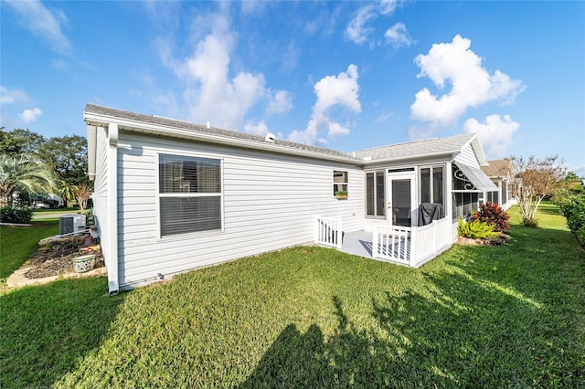 rear view of house featuring a lawn, cooling unit, and a sunroom