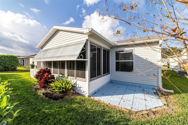 back of house featuring a lawn, a sunroom, cooling unit, and a patio