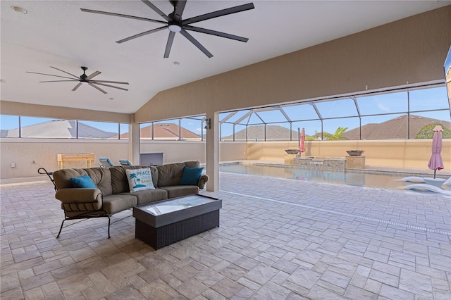 view of patio with an outdoor living space, a mountain view, ceiling fan, a swimming pool with hot tub, and a lanai