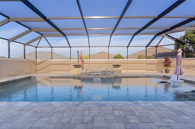 view of pool with a hot tub, glass enclosure, and a patio area