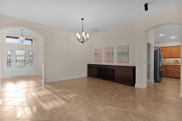 tiled entryway with a notable chandelier