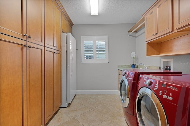 washroom featuring washer and dryer, light tile patterned flooring, cabinets, and a textured ceiling