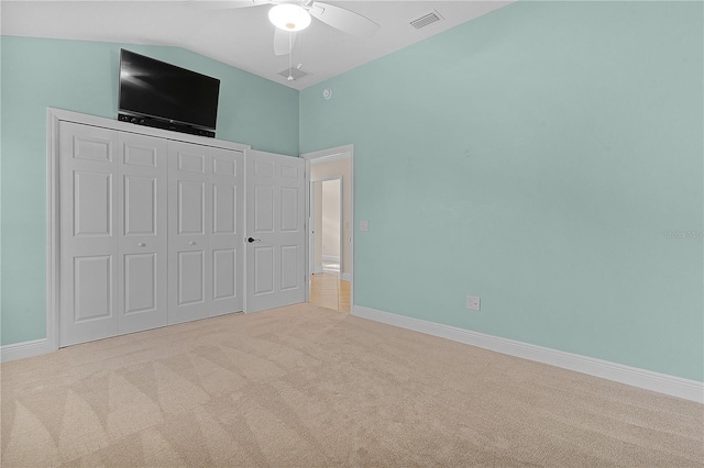 unfurnished bedroom featuring a closet, vaulted ceiling, ceiling fan, and light colored carpet