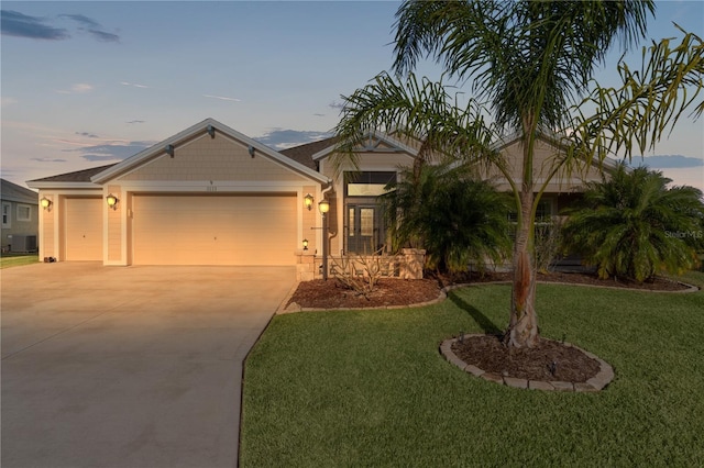 view of front of home featuring a lawn, central AC, and a garage