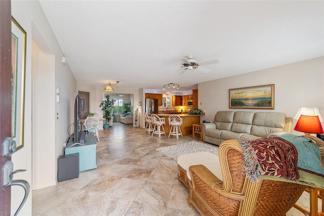 living room with a textured ceiling and ceiling fan