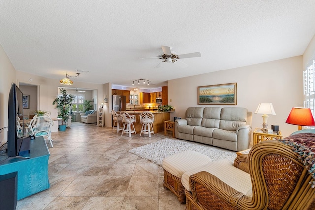 living room featuring a wealth of natural light, ceiling fan, and a textured ceiling