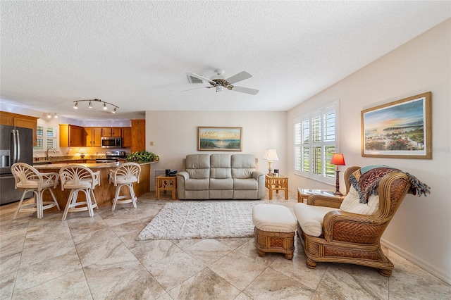 living room with ceiling fan, sink, and a textured ceiling