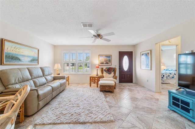 living room featuring a textured ceiling, ceiling fan, and a healthy amount of sunlight