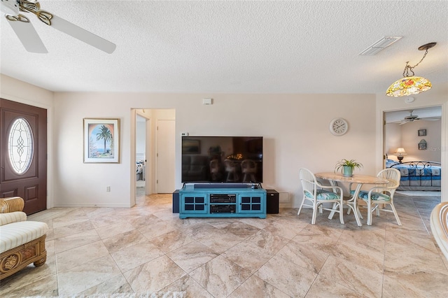 living room with ceiling fan and a textured ceiling