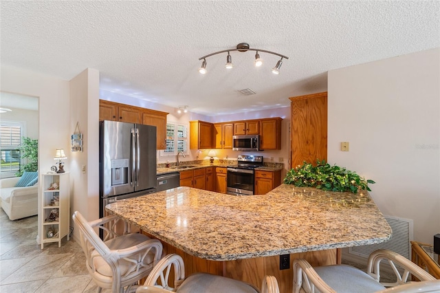 kitchen featuring light stone counters, sink, kitchen peninsula, and stainless steel appliances